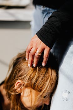 Close-up of a comforting hand on a woman's head during an emotional moment.