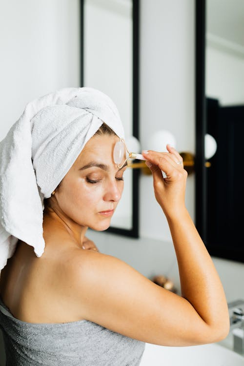 Free A Woman Wearing a Head Towel Massaging Face Stock Photo