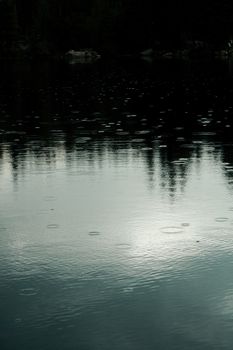 美国怀俄明州科迪，宁静的湖面上，树木倒映，雨滴柔和