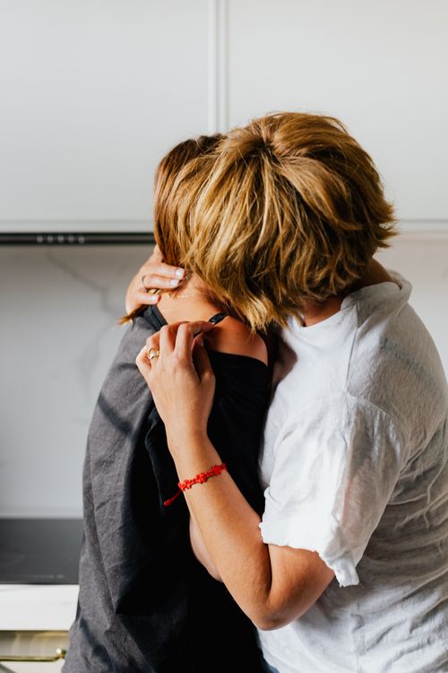 Free Two women sharing an affectionate moment in a kitchen setting. Stock Photo