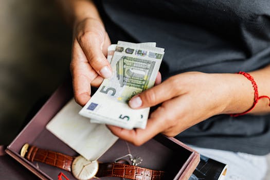 Close-up of hands counting euro notes above a wristwatch in a box.