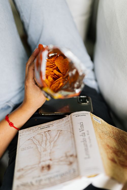 Free A person reading with snacks and a smartphone, relaxed atmosphere. Stock Photo