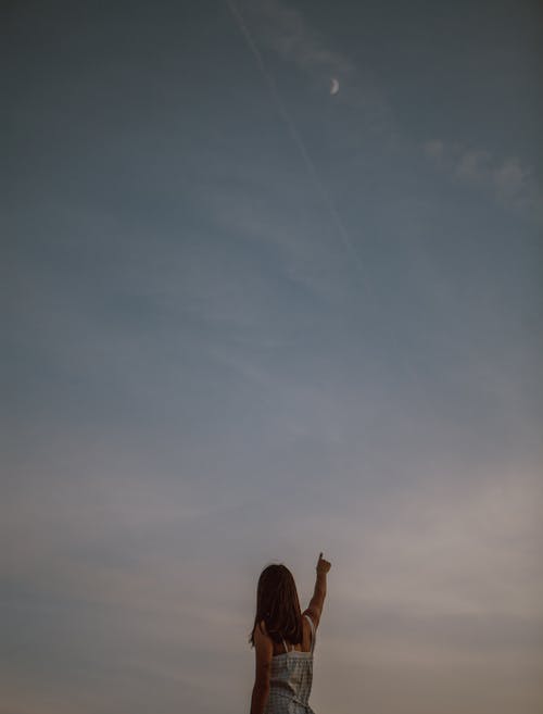 Free Woman pointing at sunset sky in evening Stock Photo