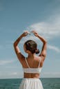 海边明媚的夏日天空下，一名女子自由地举起双臂