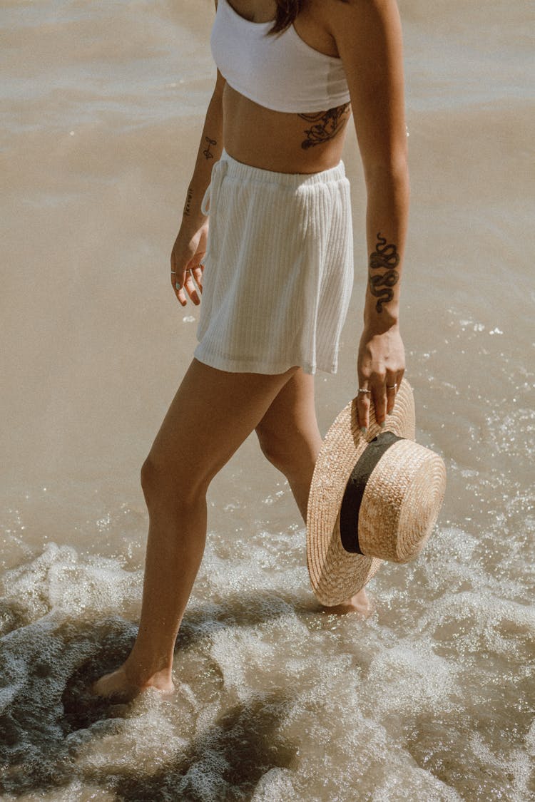 Woman In White And Blue Stripe Skirt And Brown Sun Hat Standing On Water