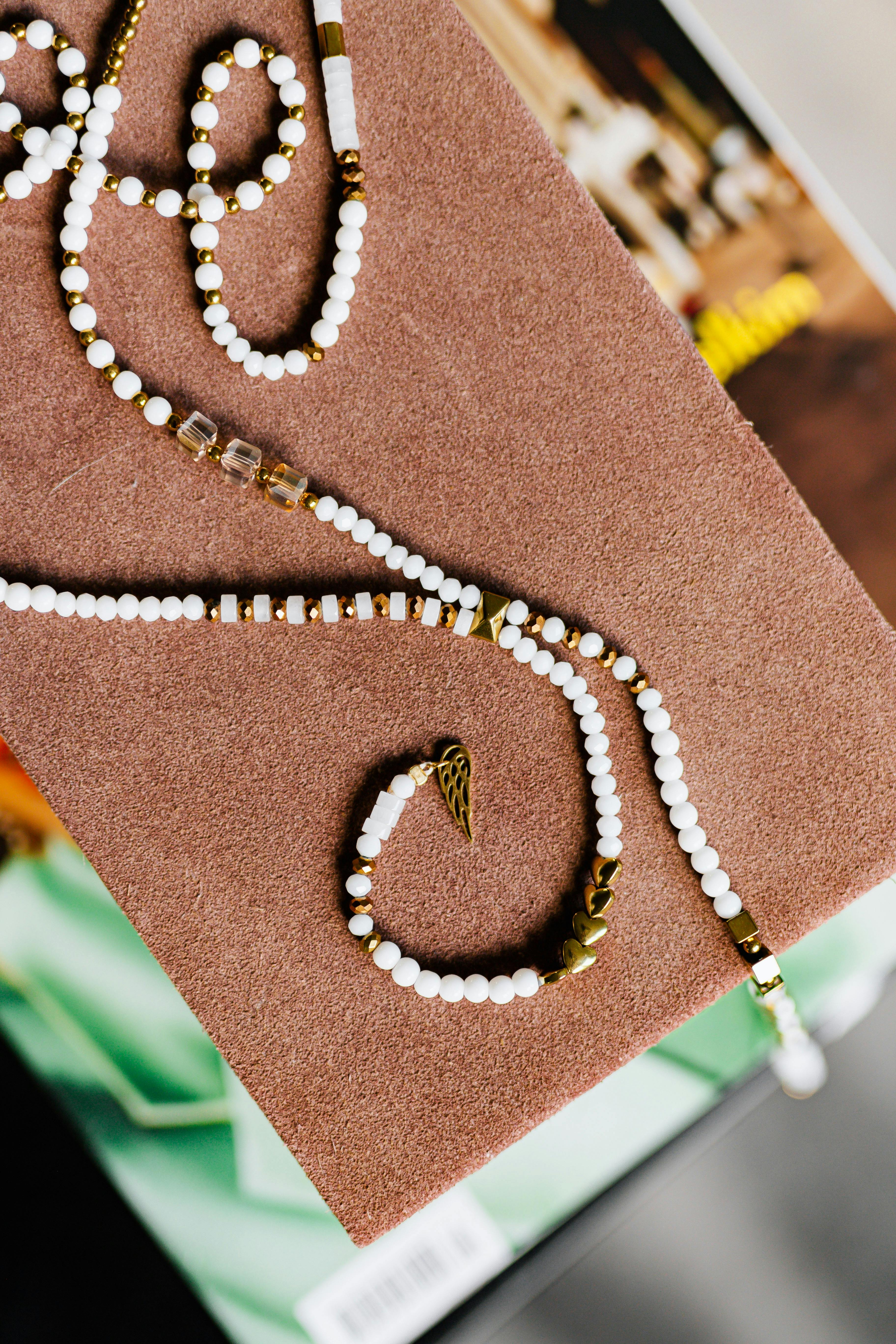 a string of white and gold beads on a brown box