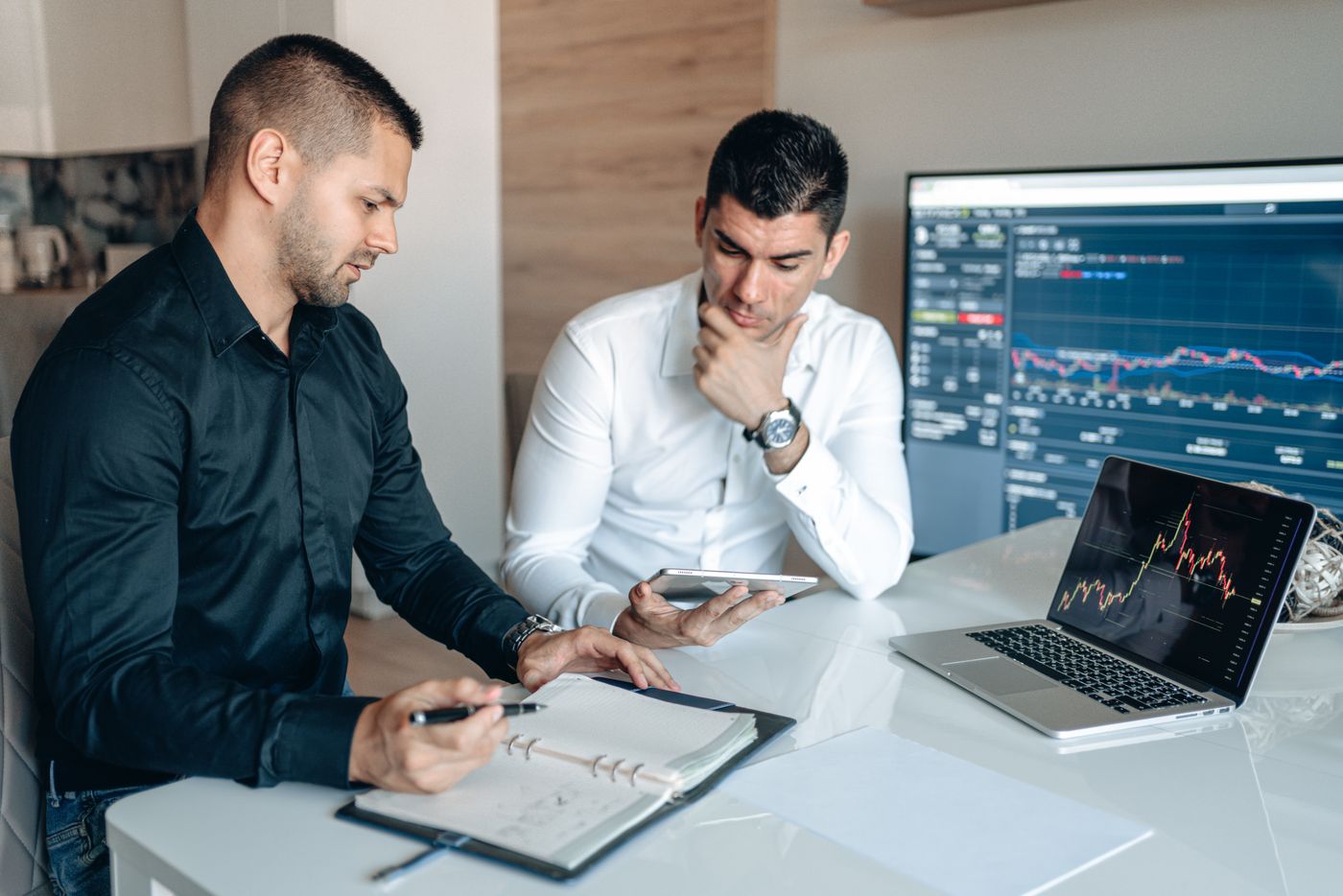 Dois profissionais analisando métricas em uma mesa com notebook e tablet