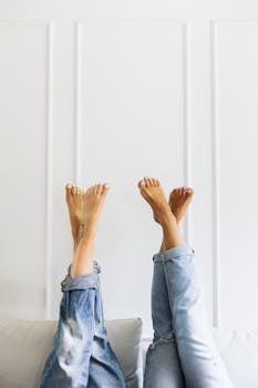 Two people relaxing with their feet up in denim jeans against a white backdrop.