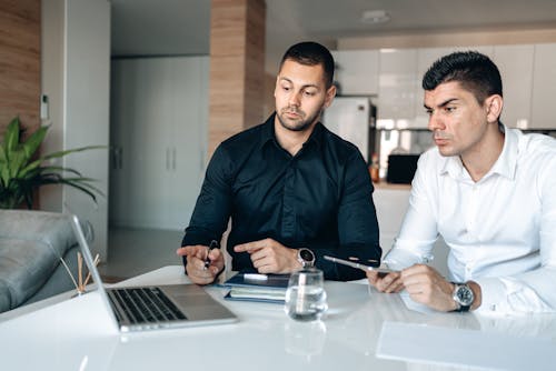 Man in Black Dress Shirt Holding Pen and Macbook Pro