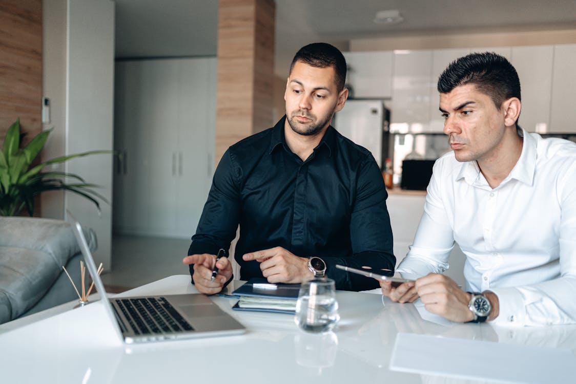 Uomo In Camicia Di Vestito Nera Che Tiene Penna E Macbook Pro