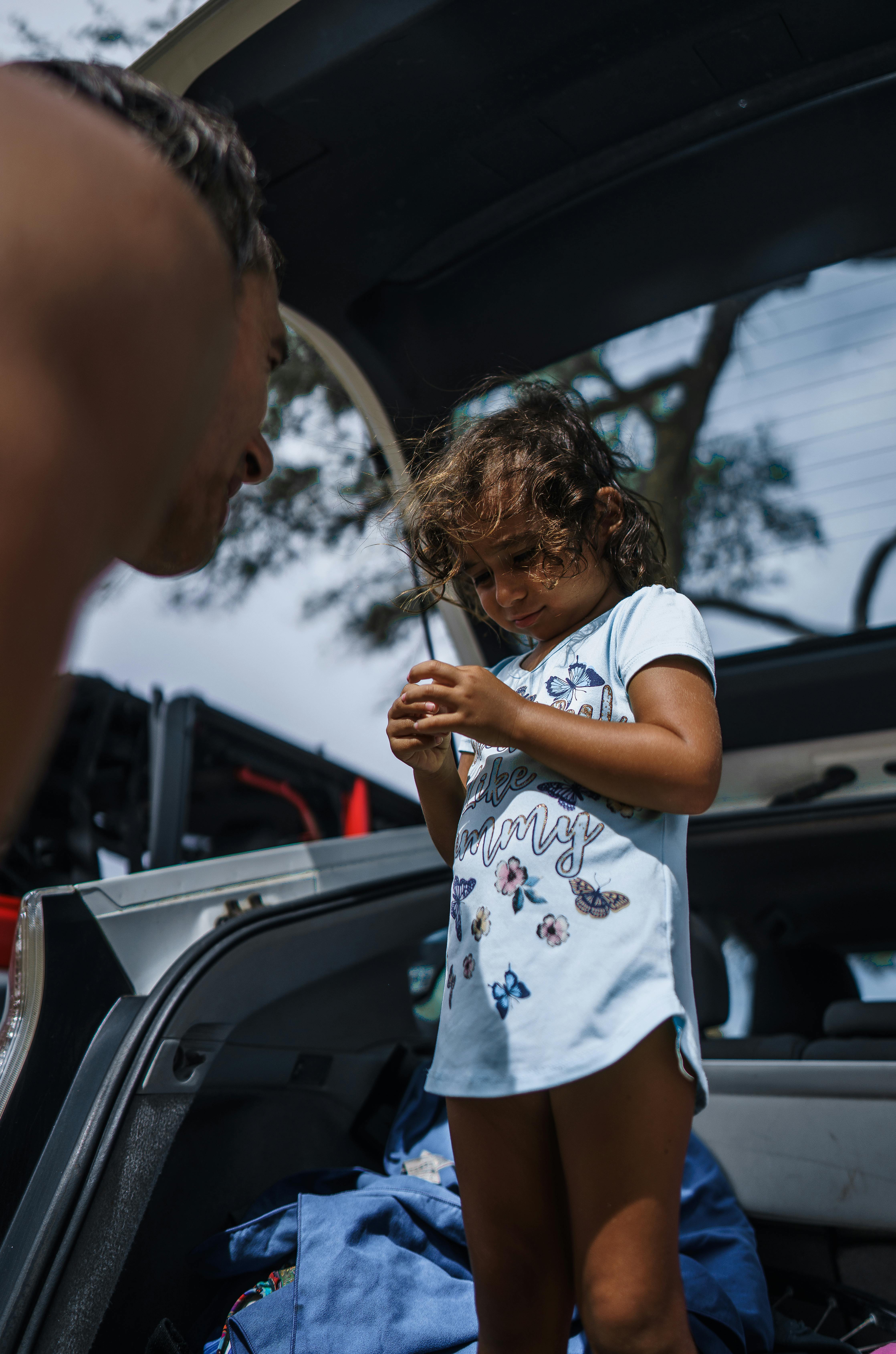 little girl standing in car trunk