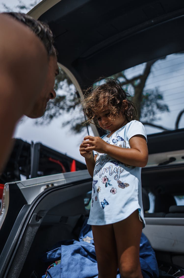 Little Girl Standing In Car Trunk