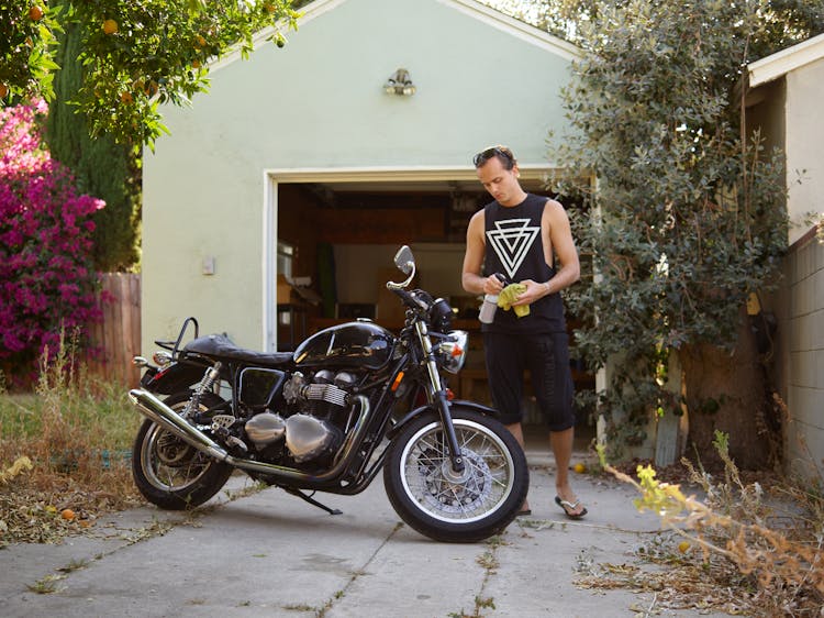 A Man In Black Sleeveless Shirt Cleaning A Motorcycle