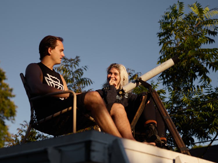 A Man And A Woman Sitting Near A Telescope