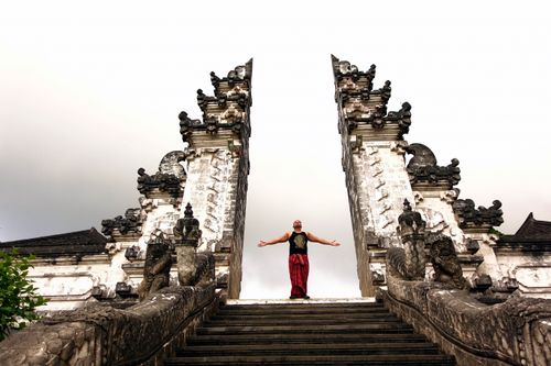 Free A man stands with arms outstretched at Pura Lempuyang temple in Bali, Indonesia, highlighting its grand architecture. Stock Photo