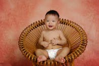 Baby Sitting on Brown Round Bamboo Chair