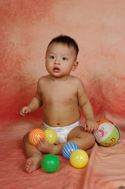 A Sitting Baby Surrounded with Balls