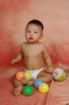 可爱的宝宝坐在明亮的球和玩具之间，显得天真又好玩