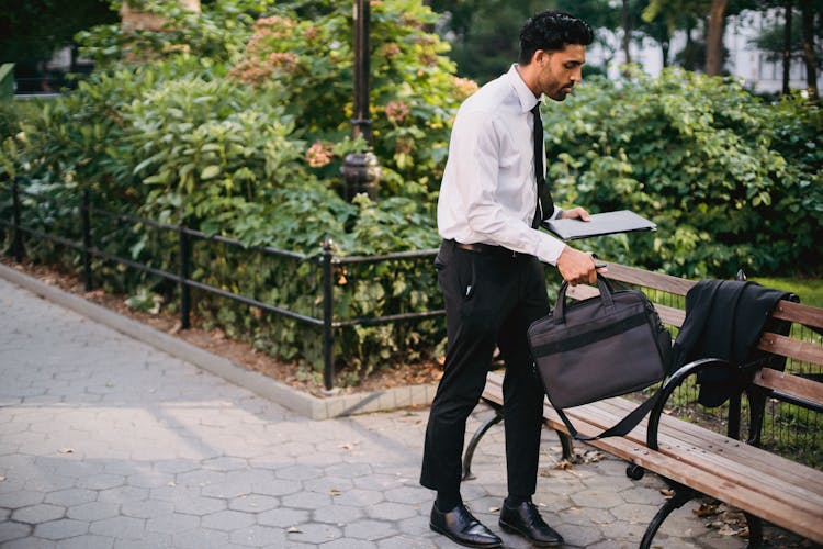 Man In Business Attire Holding A Bag And A Notebook 