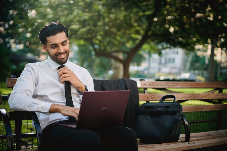 Man In White Shirt Sitting On Bench With Laptop 