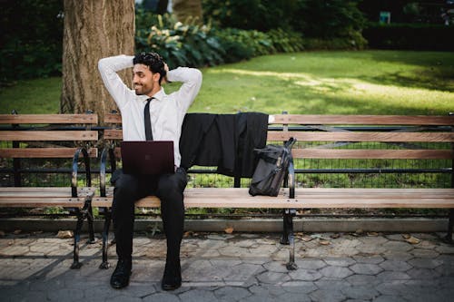 Free A Man Smiling Sitting on a Wooden Bench Stock Photo