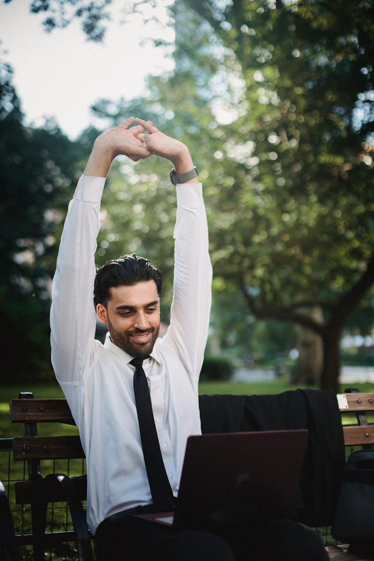 Man Sitting On Bench Stretching Arms Up