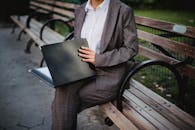 A Person in Gray Suit Holding a Black Folder Sitting on a Bench