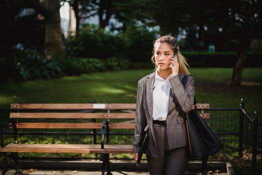 一位穿着西装的职业女性在城市公园里使用智能手机