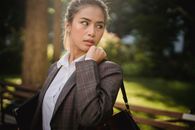 一位穿着正式服装的女商人在户外，看起来深思熟虑而自信