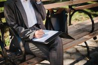 Woman Sitting on a Park Bench Filing Out Paperwork