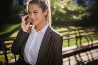 阳光明媚的公园里，一位自信的女商人微笑着打电话