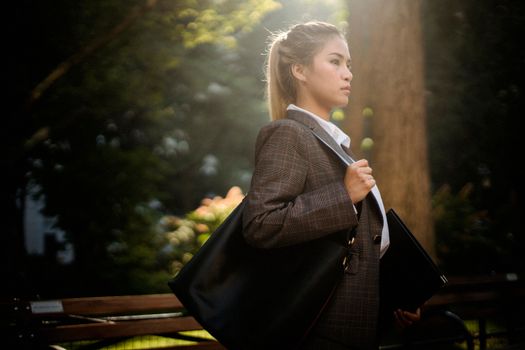 一位穿着西装的年轻女子，自信地走在阳光明媚的公园里