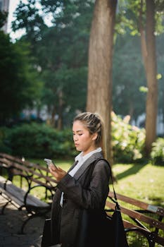 一位自信的女商人在阳光明媚的公园里查看智能手机