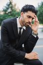 一名男子身穿黑色西装，在户外沉思