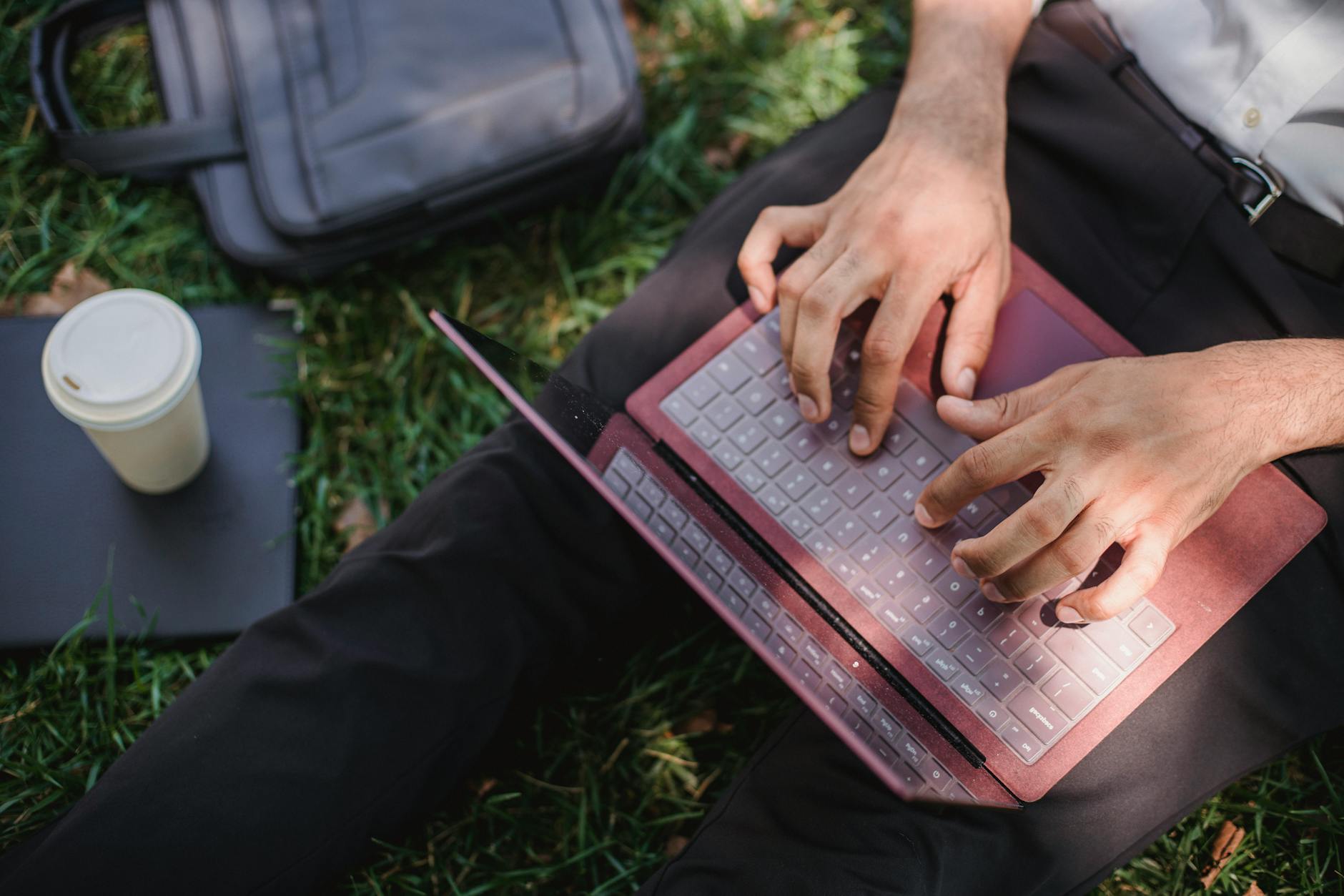 Person Typing on a Maroon Laptop