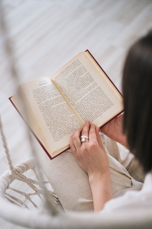 Free A close-up view of a person holding and reading a book indoors, capturing a serene moment. Stock Photo