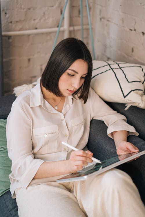 A Woman in Beige Long Sleeves Drawing on Digital Tablet