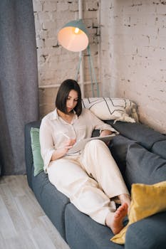 Woman using an iPad with an Apple Pencil on a couch, styled for a cozy work-from-home setting.