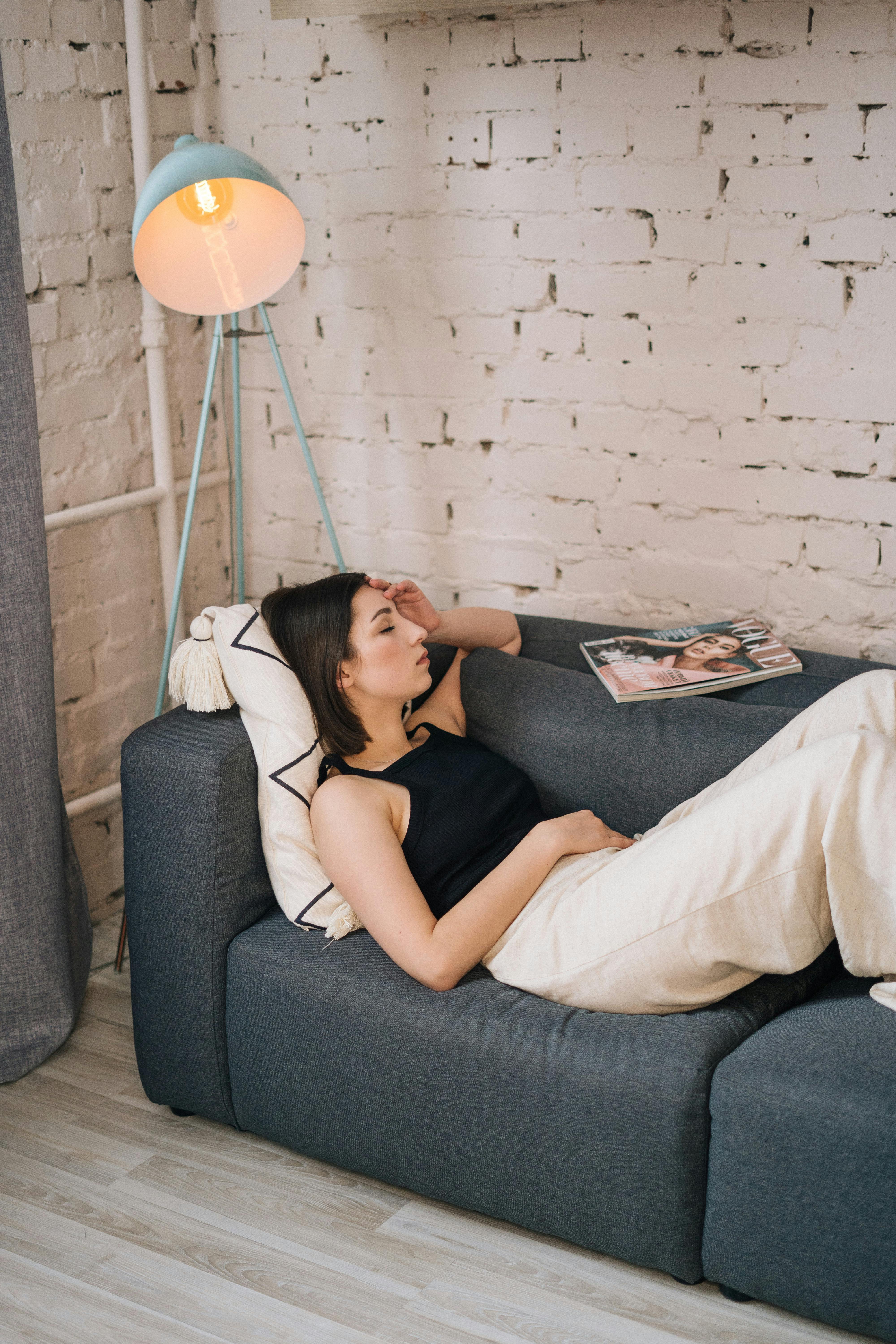Free A Woman Lying on the Gray Couch with Her Eyes Closed Stock Photo