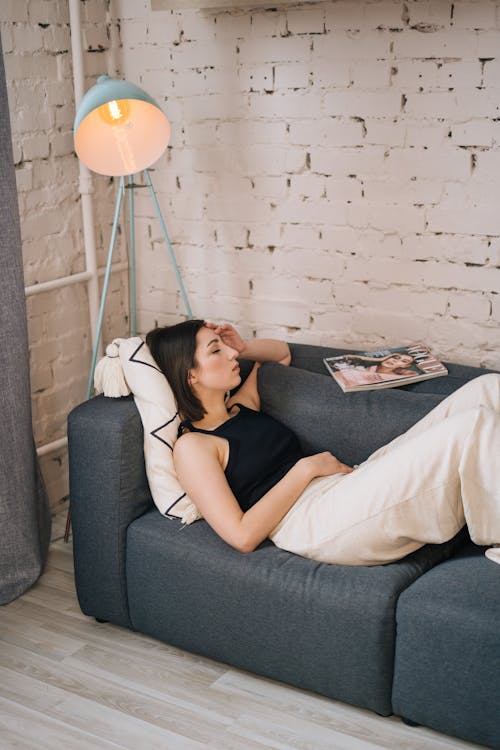 Free A Woman Lying on the Gray Couch with Her Eyes Closed Stock Photo
