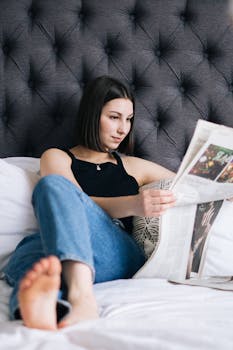 Casual scene of a young woman reading a newspaper in a cozy bedroom setting.