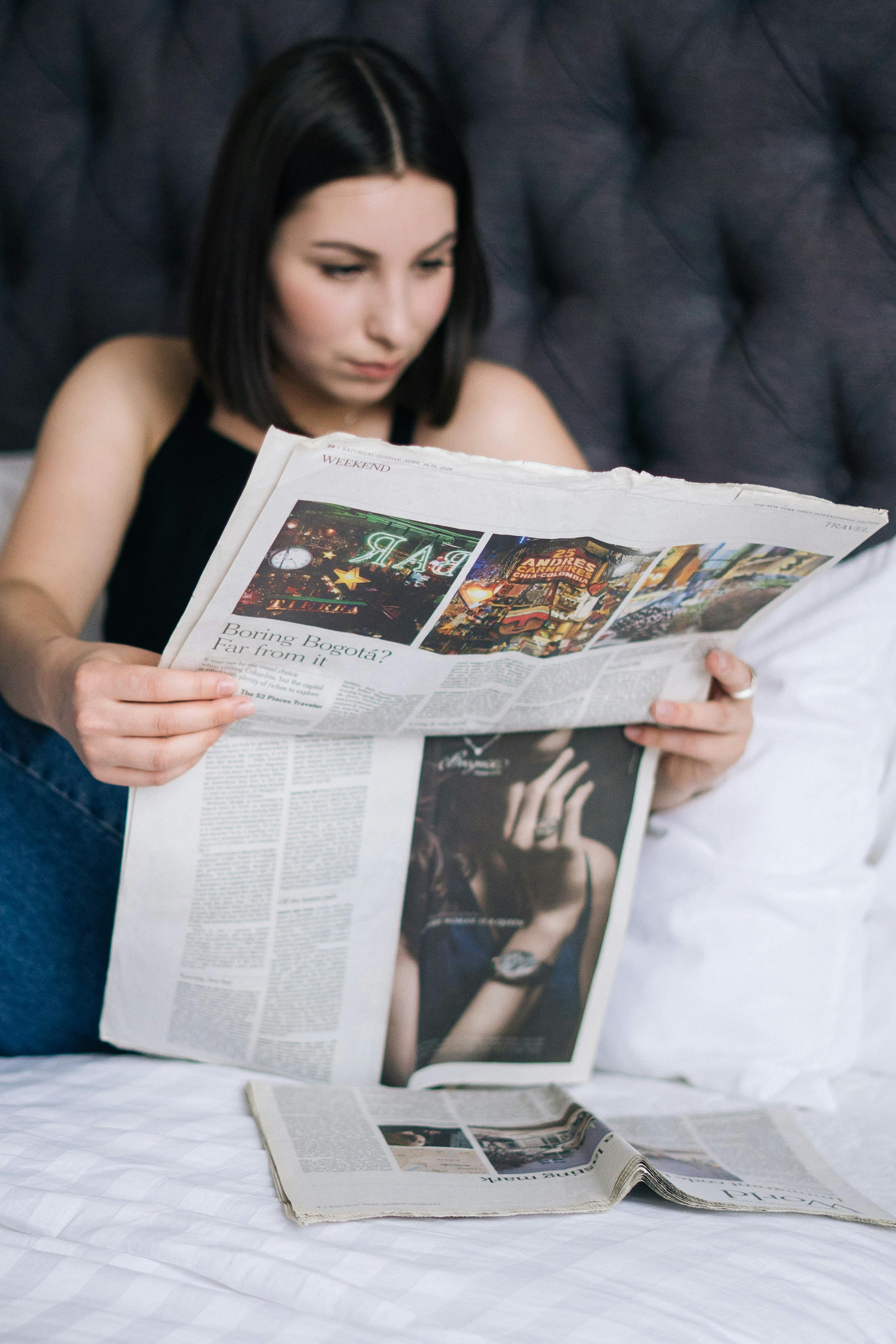 a woman reading the newspaper in bed