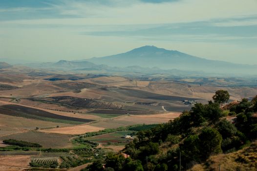 Aerial landscape with rolling hills and Mount Etna in the distance, captured in Catania, Sicily.