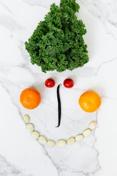 Playful arrangement of fruits and vegetables forming a face on marble surface.