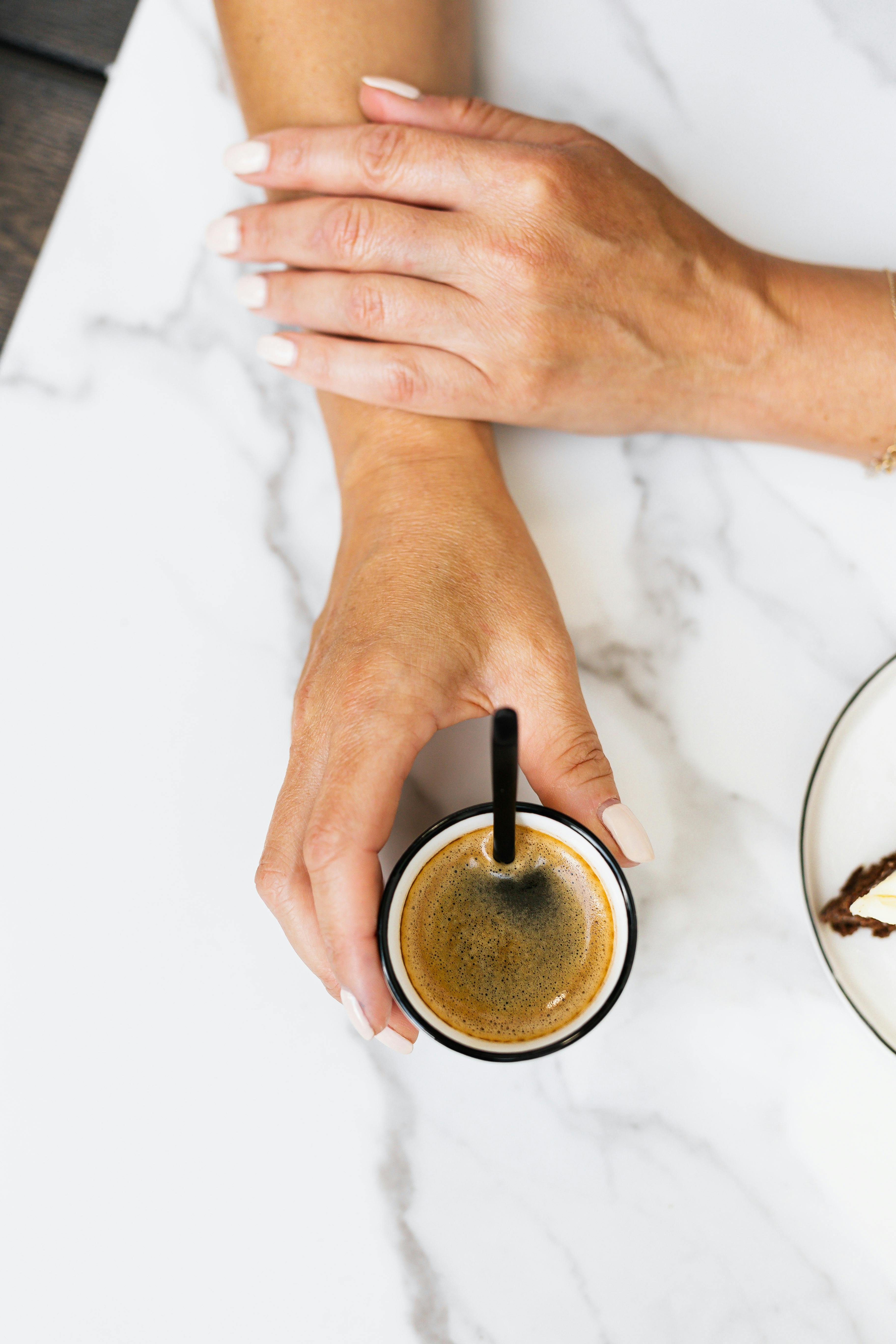 双手放在大理石桌上，从上方捕捉优雅的咖啡时刻
