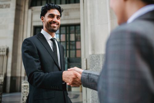 Free Two business professionals shake hands confidently in an urban setting. Stock Photo