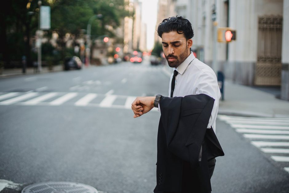 Confident young businessman checking his watch while standing on an urban street. Confident young businessman checking his watch while standing on an urban street.