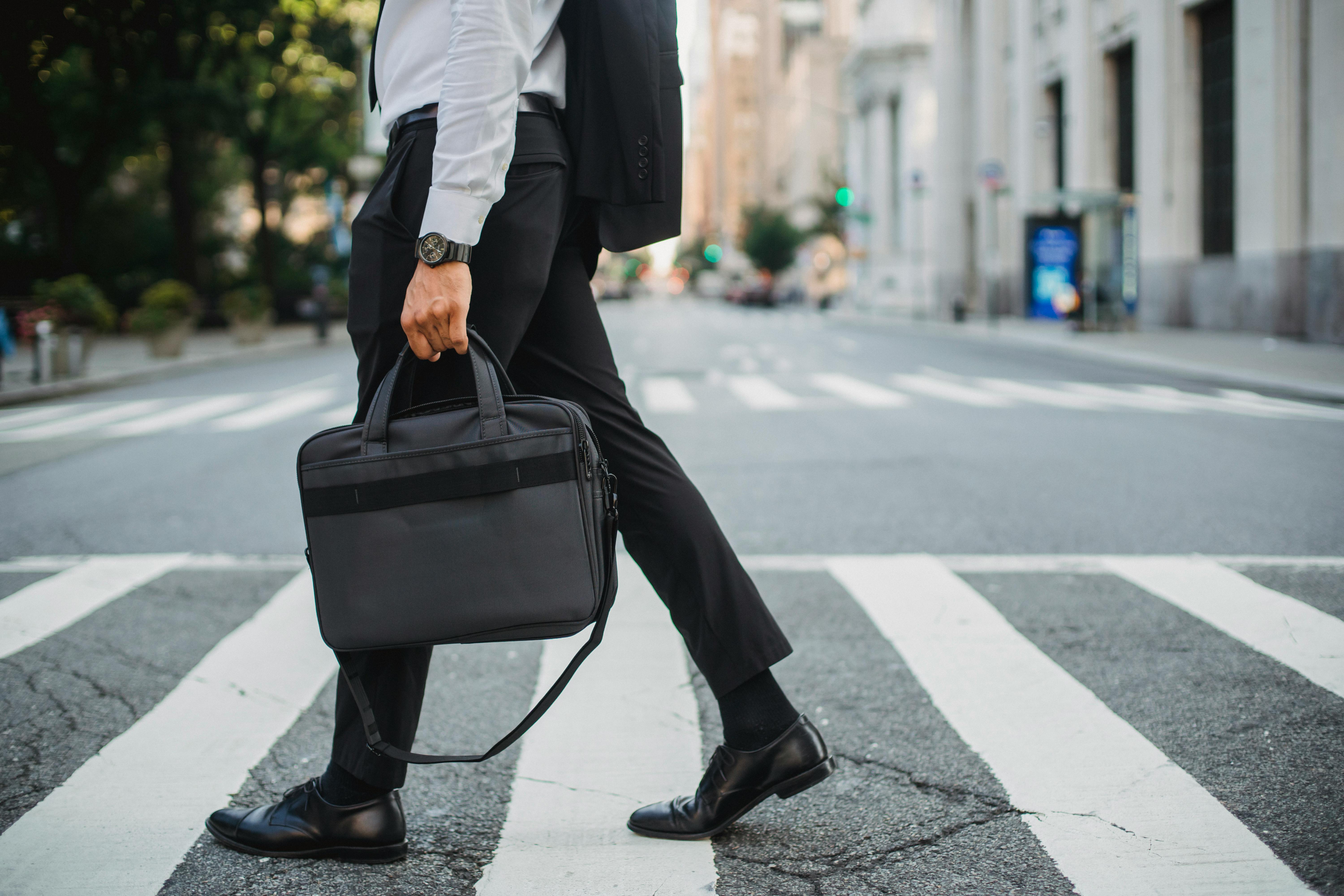 businessman carrying a laptop bag crossing the street