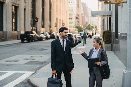 两名穿着公司服装的商务人士在光天化日之下，于城市街道上边走边讨论想法
