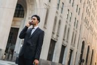 一位穿着西装的专业人士在城市街道上打电话，捕捉着城市商业生活的瞬间